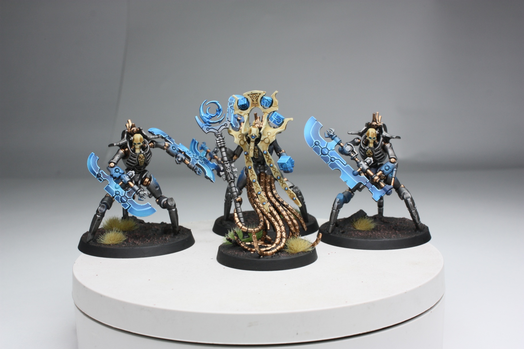 Necron characters in black armour with glowing blue weapons and a cryptek