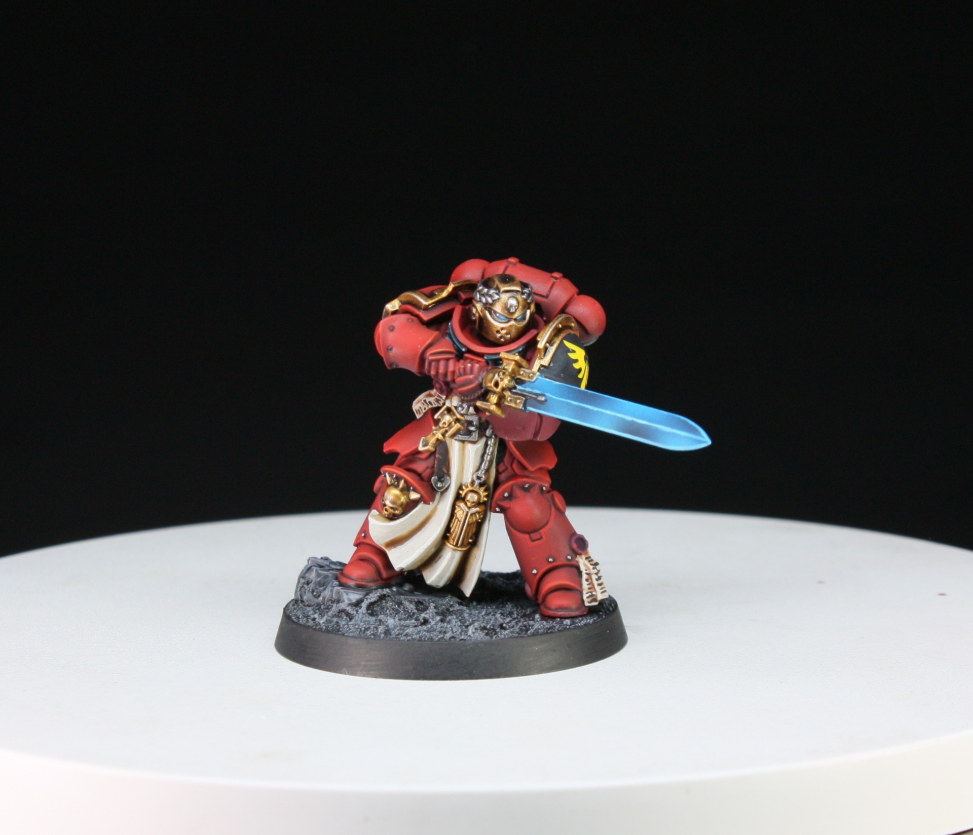 Blood Angels Captain in red armour with golden helmet and glowing blue power sword